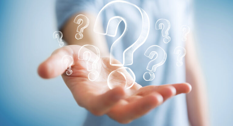 Businessman,On,Blurred,Background,Holding,Hand,Drawn,Question,Marks