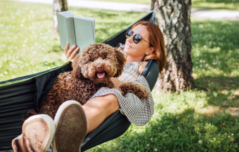 Woman,Reading,Book,Relaxing,In,Hammock,With,Her,Fluffy,Brown